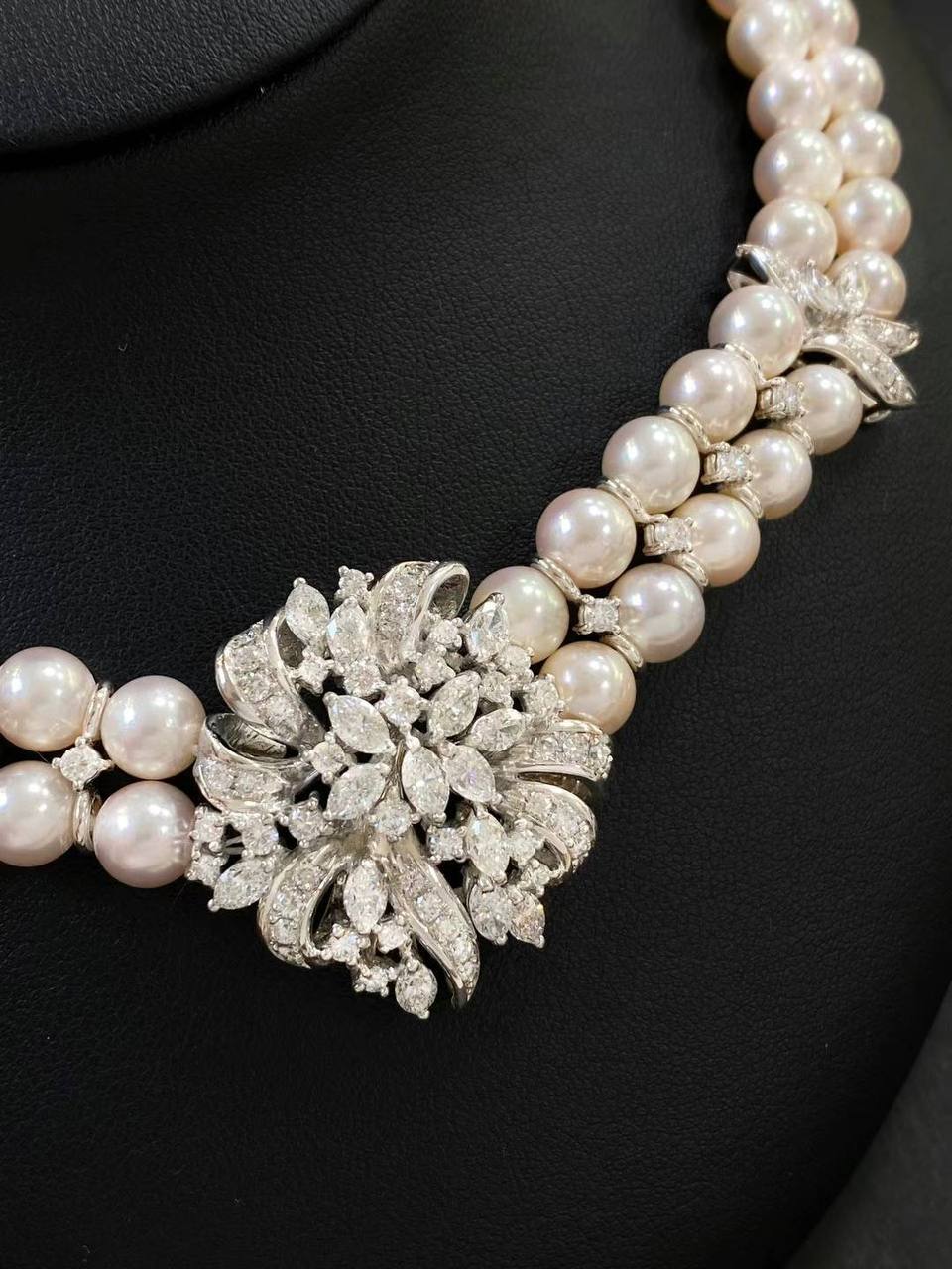Double-strand pearl necklace with diamond accents and a floral diamond brooch centerpiece on a black display bust